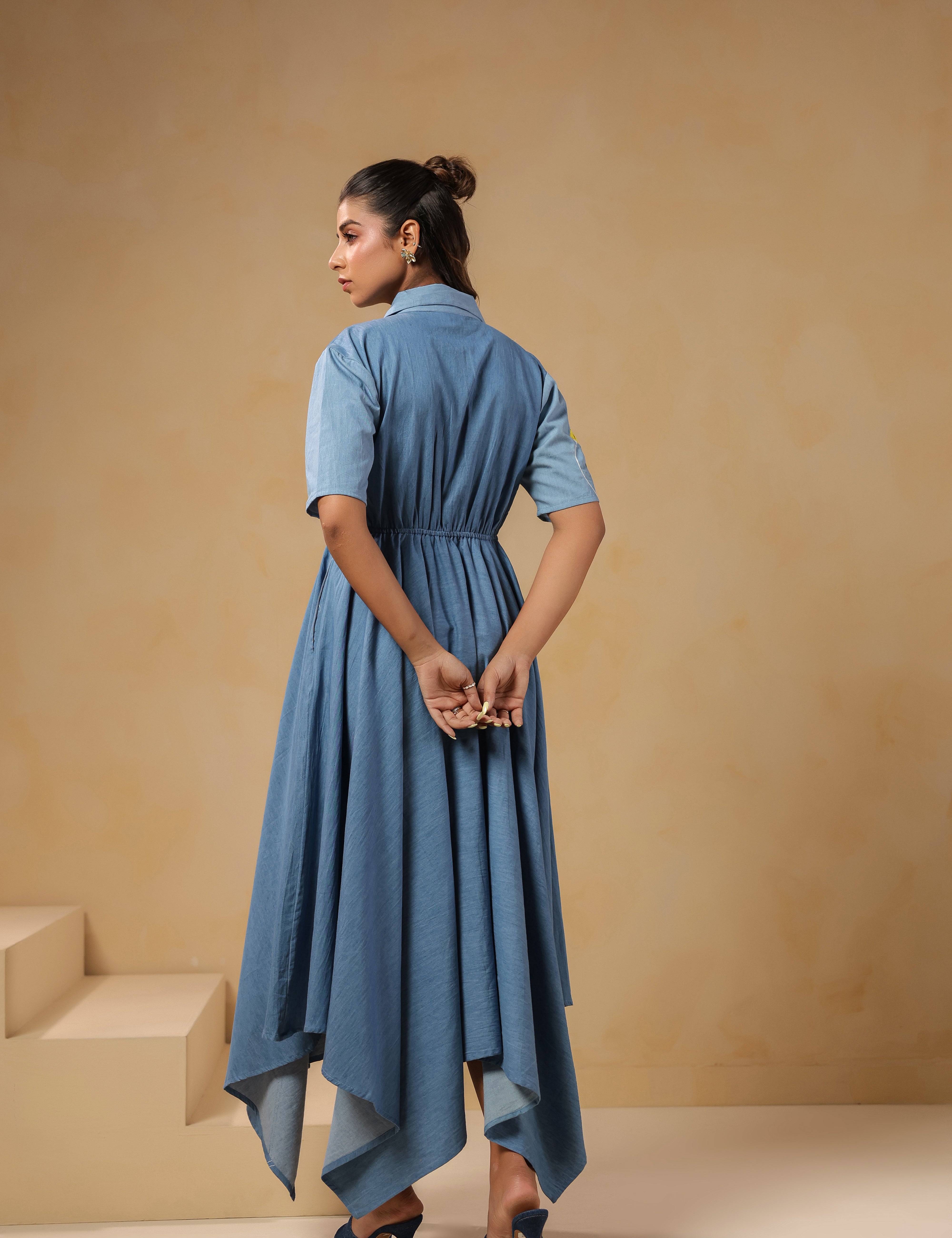 Back view of the Daisydrift Handkerchief Dress featuring a flowing handkerchief hemline, short sleeves, and gathered waist detail in lightweight denim.