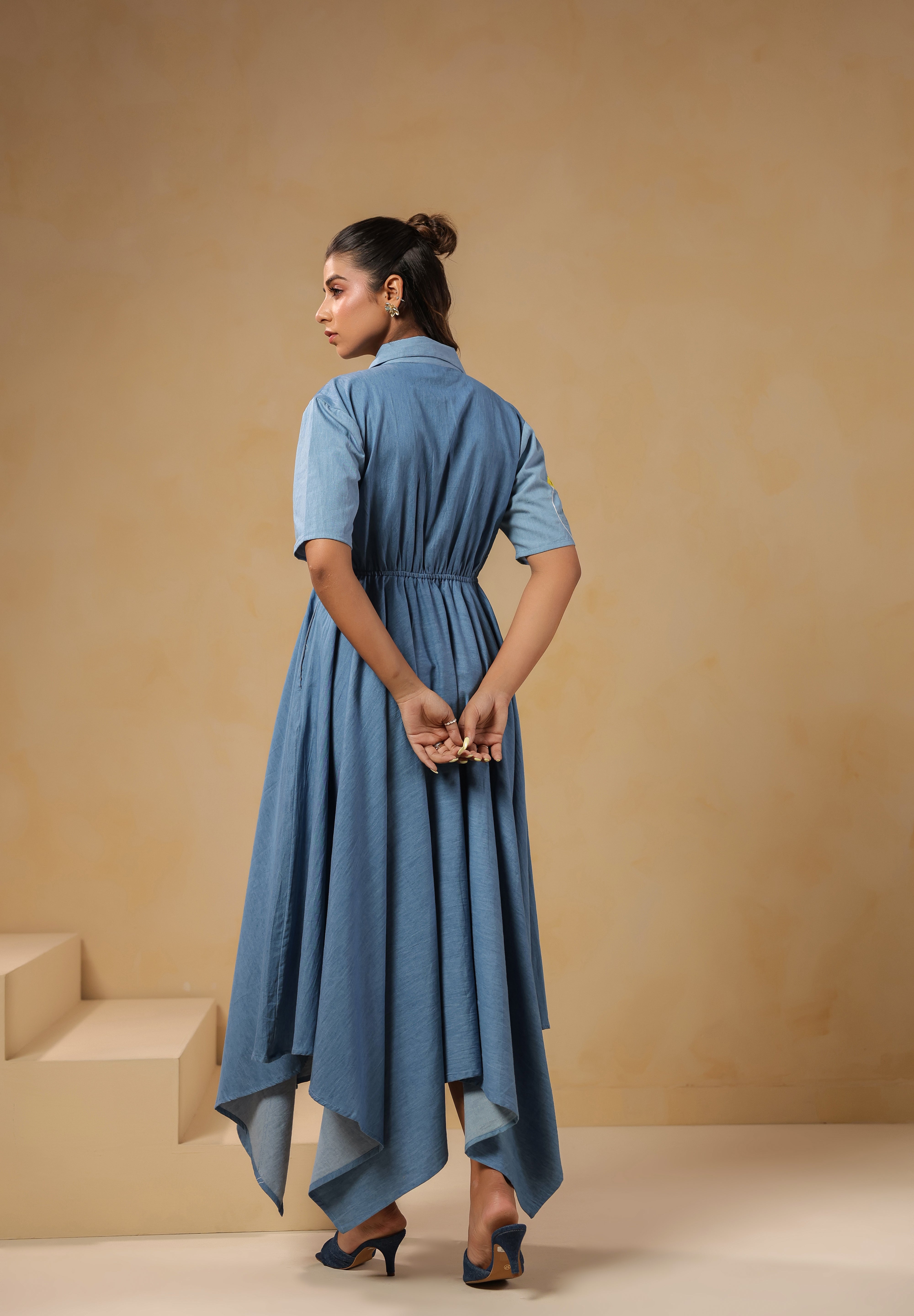 Back view of the Daisydrift Handkerchief Dress featuring a flowing handkerchief hemline, short sleeves, and gathered waist detail in lightweight denim.
