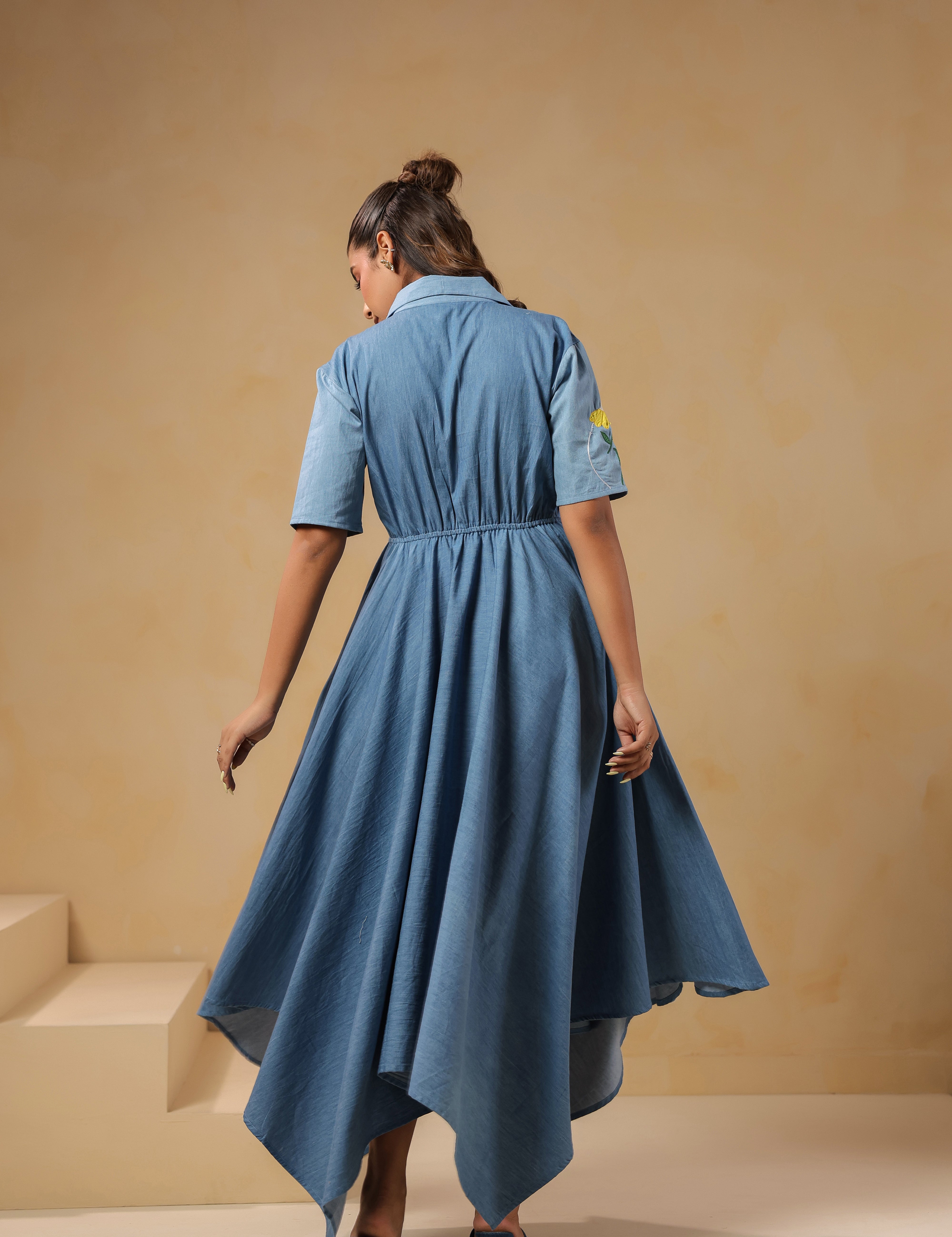Back view of the Daisydrift Handkerchief Dress featuring a flowing handkerchief hemline, short sleeves, and gathered waist detail in lightweight denim.