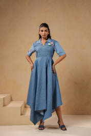 Model posing in the Daisydrift Handkerchief Dress, showing the structured bodice, short sleeves, floral detailing, and flared handkerchief hemline in soft denim.