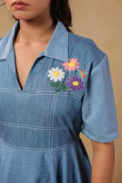 Close-up of the chest embroidery on the Daisydrift Handkerchief Dress, featuring pastel-colored daisies and delicate stitching on a collared denim neckline.