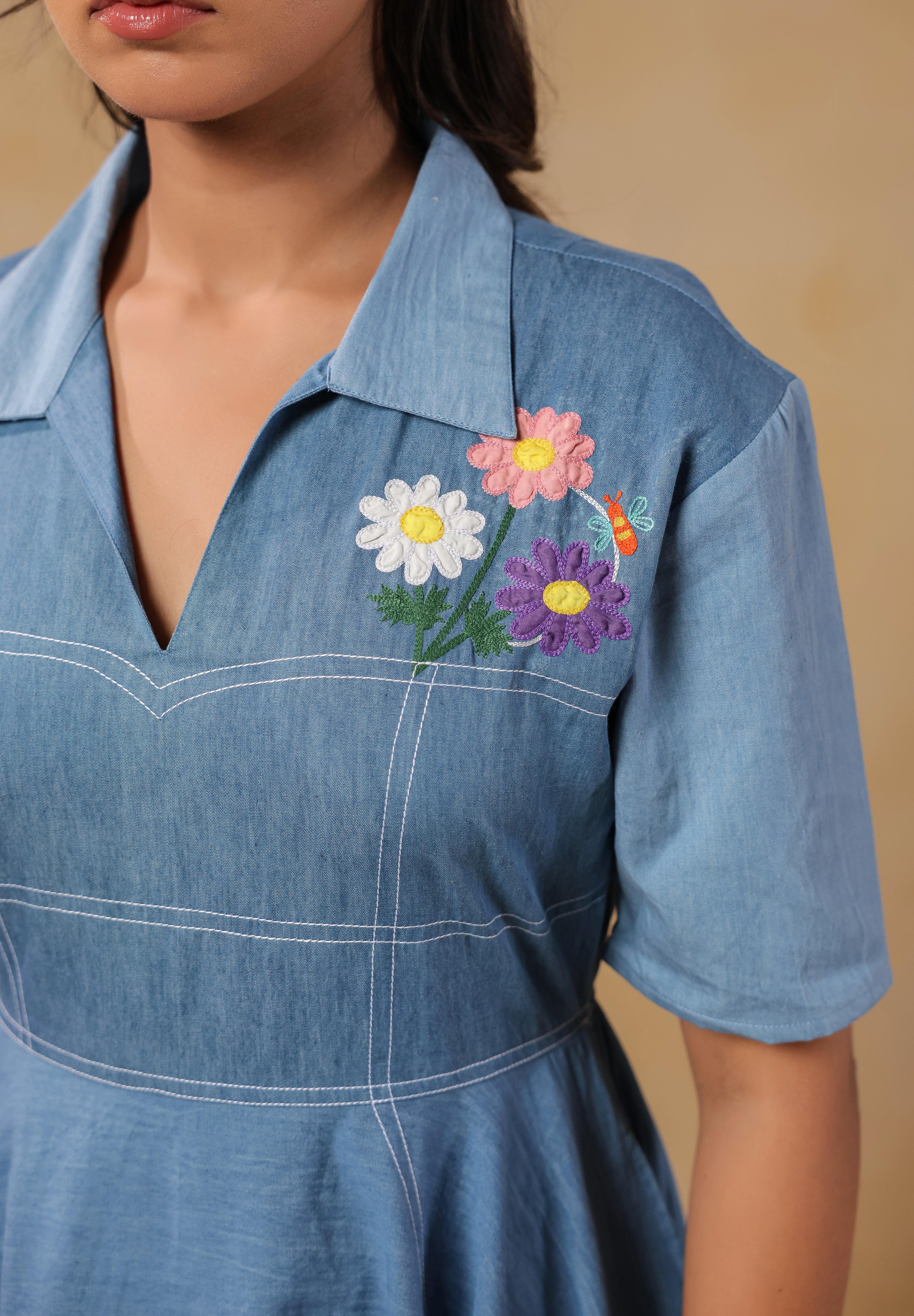 Close-up of the chest embroidery on the Daisydrift Handkerchief Dress, featuring pastel-colored daisies and delicate stitching on a collared denim neckline.