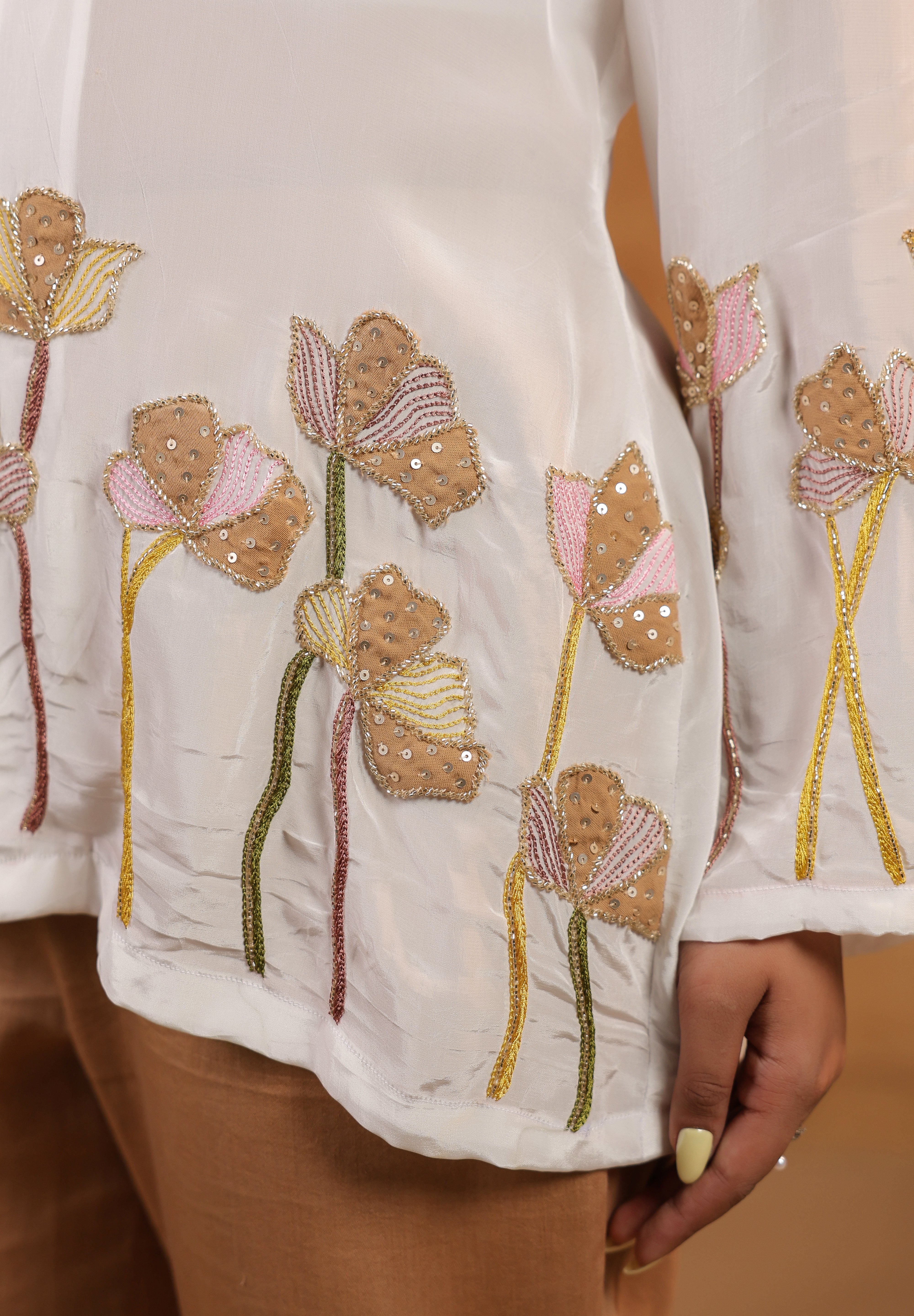 Close-up of a white garment with floral embroidery on a neutral background