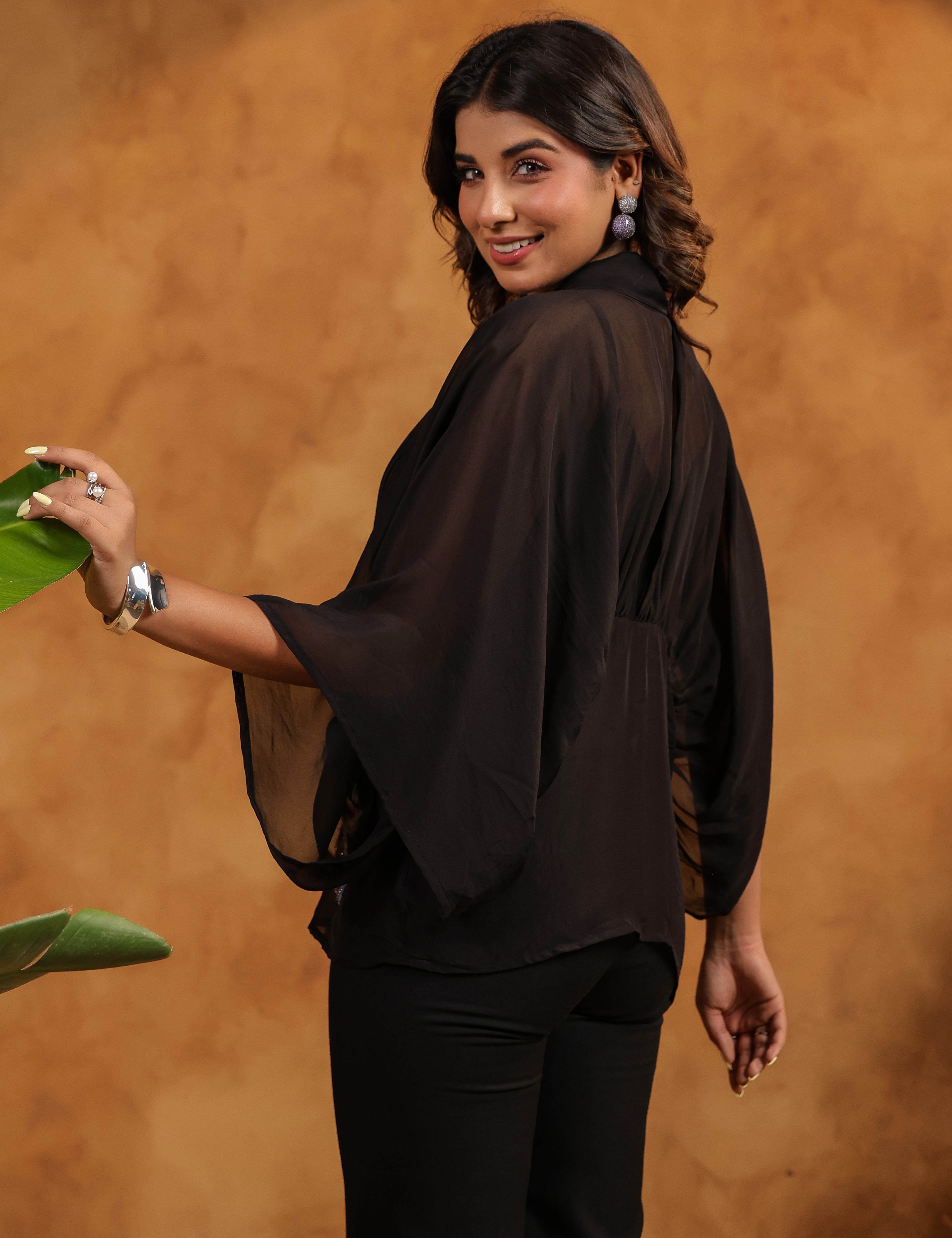 Woman wearing a black outfit against a brown background