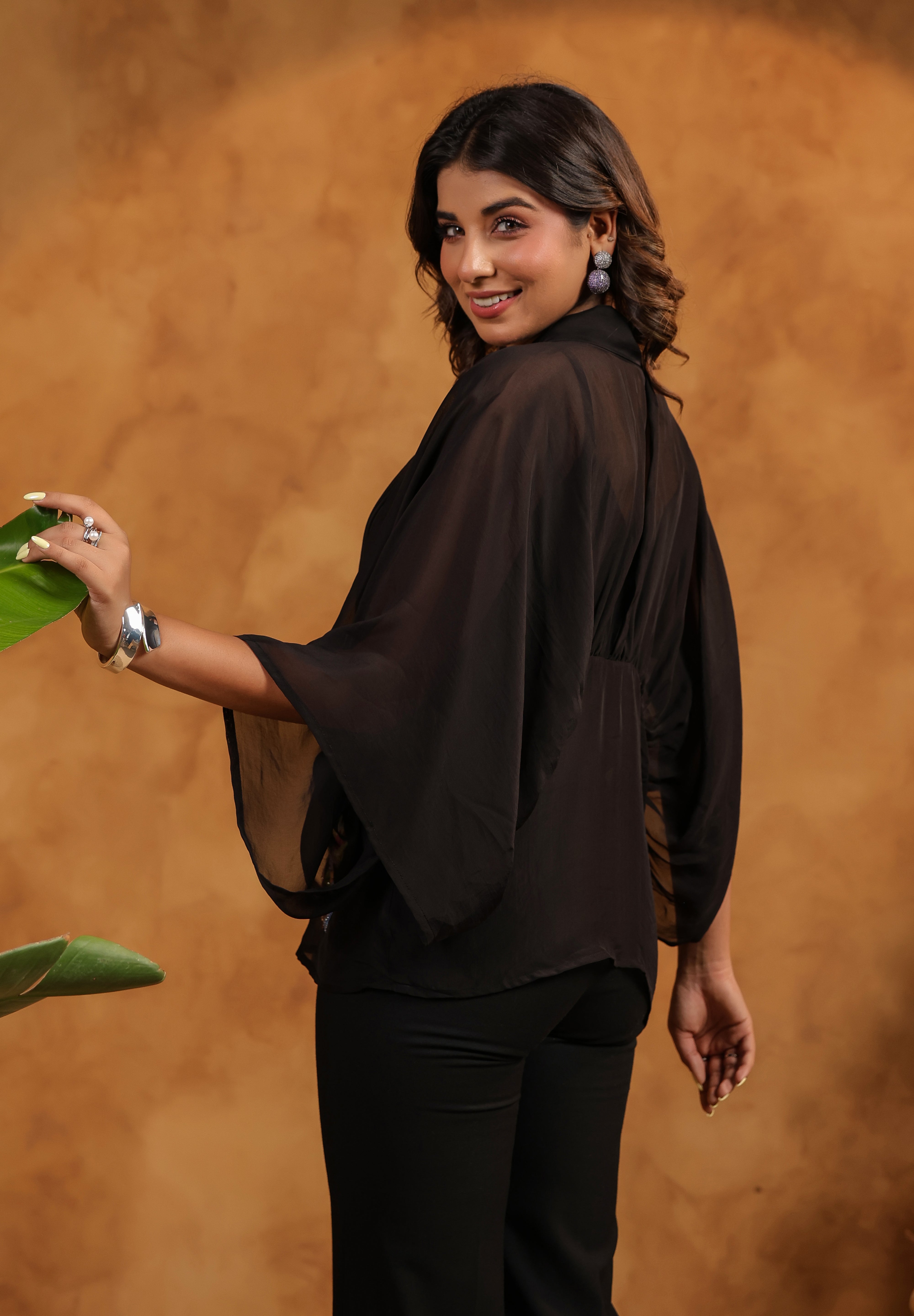 Woman wearing a black outfit against a brown background