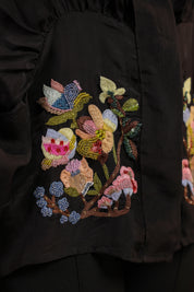 Close-up of a black garment with colorful floral embroidery