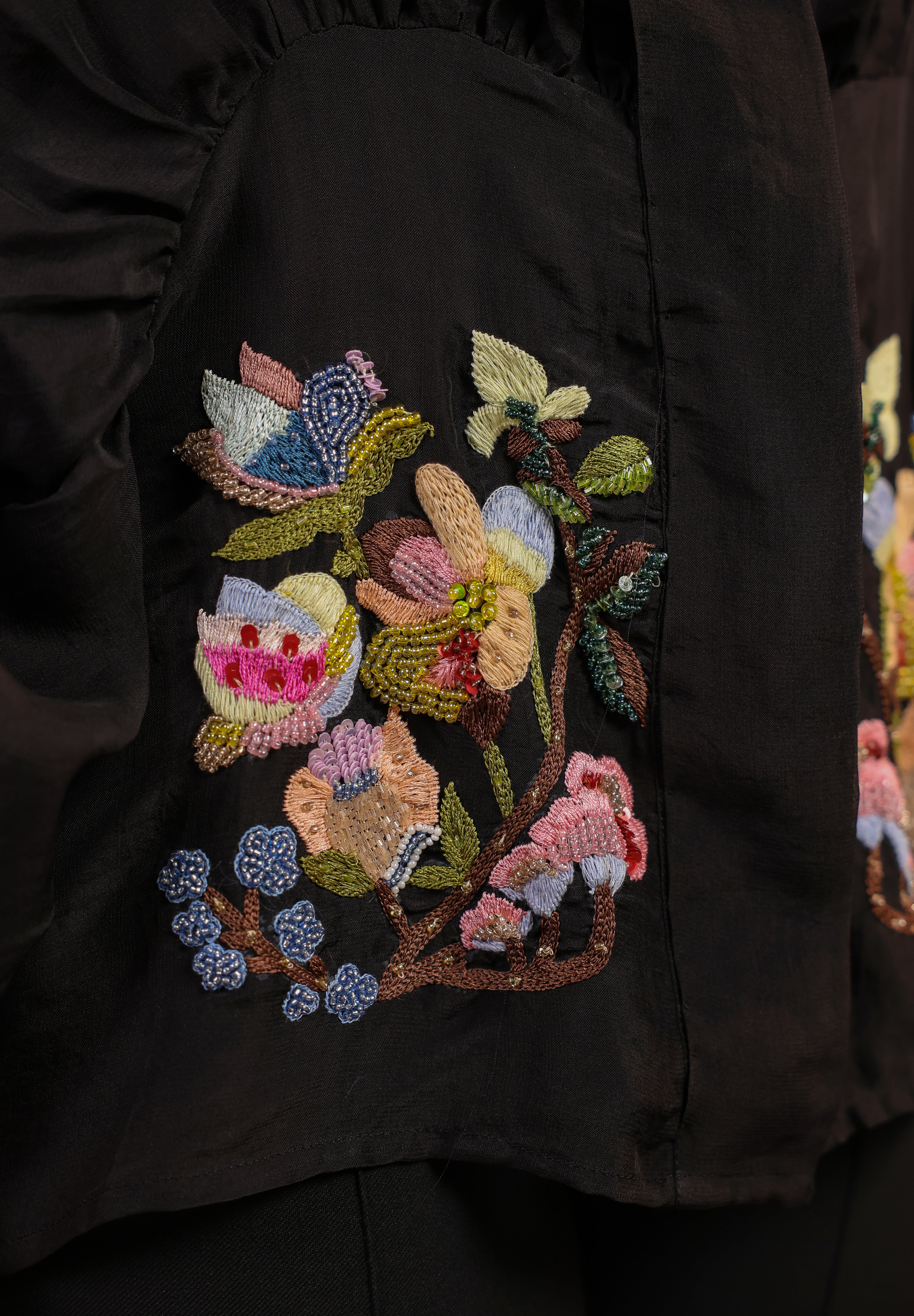 Close-up of a black garment with colorful floral embroidery
