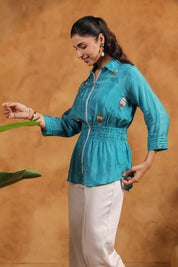 Woman wearing a teal shirt with a brown background