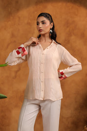Woman wearing a light-colored blouse with red accents against an orange background