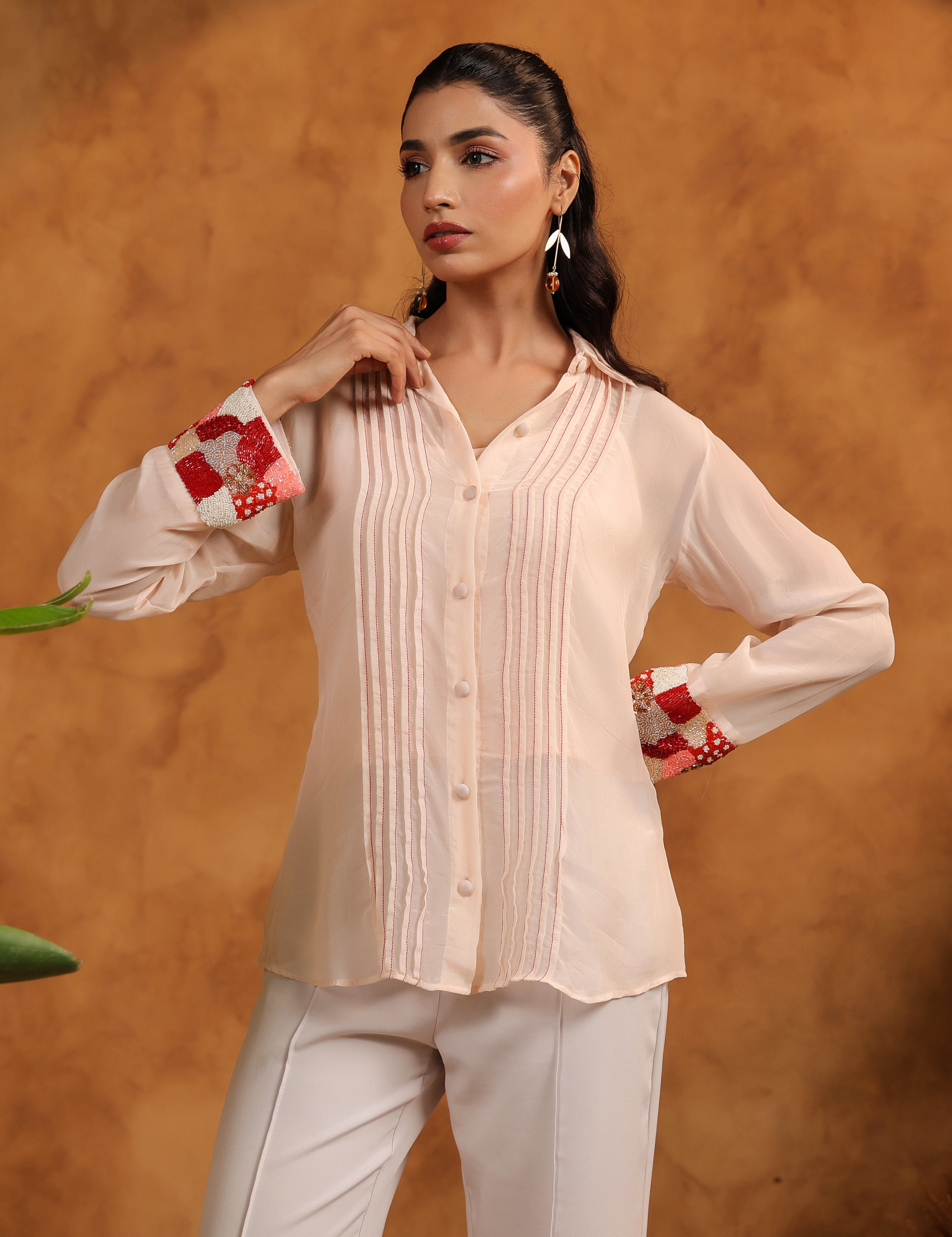 Woman wearing a light-colored blouse with red accents against an orange background