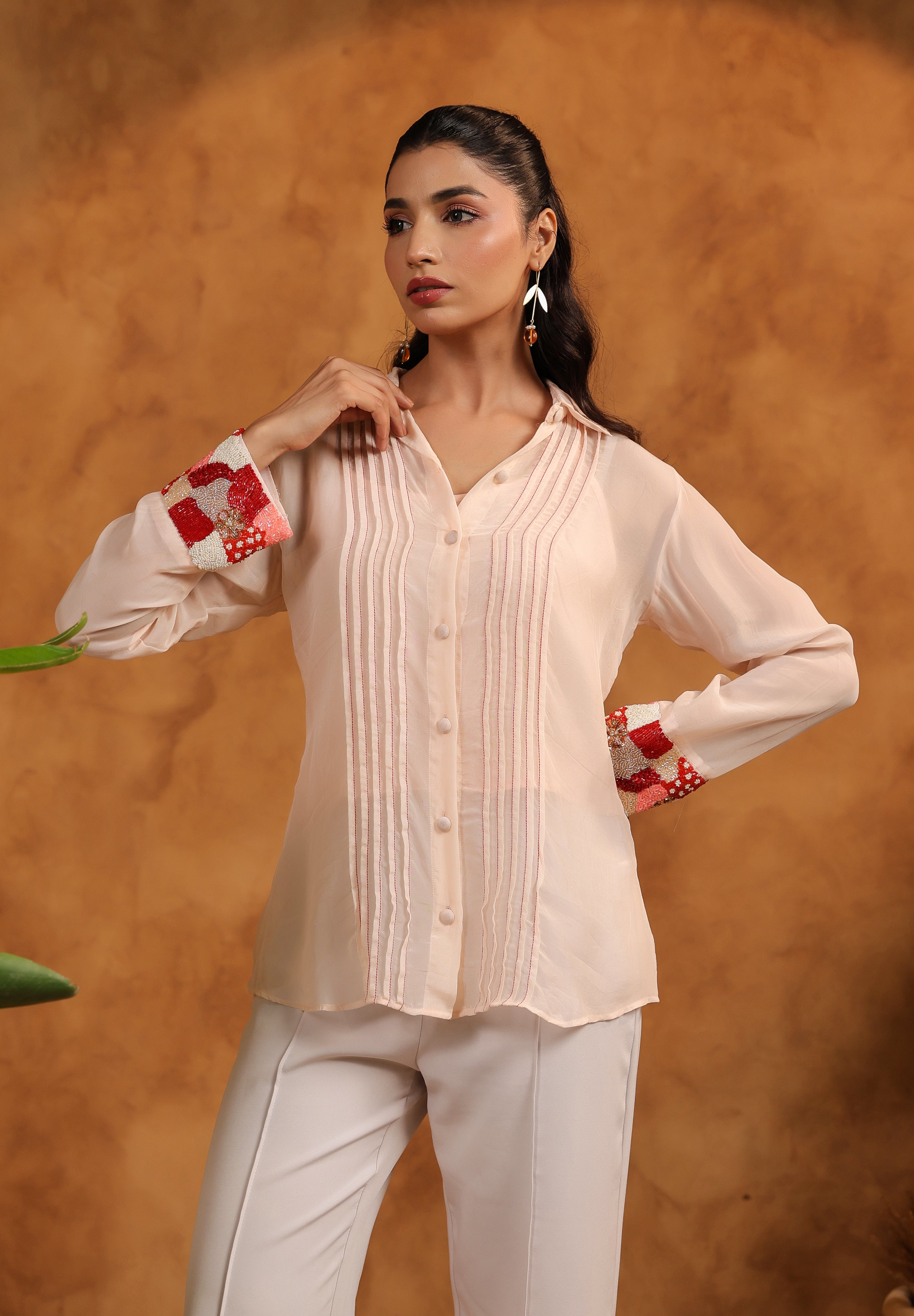 Woman wearing a light-colored blouse with red accents against an orange background