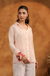 Woman wearing a light-colored outfit with red accents against a brown background