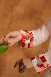 Close-up of hands wearing colorful embroidered cuffs against a warm-toned background