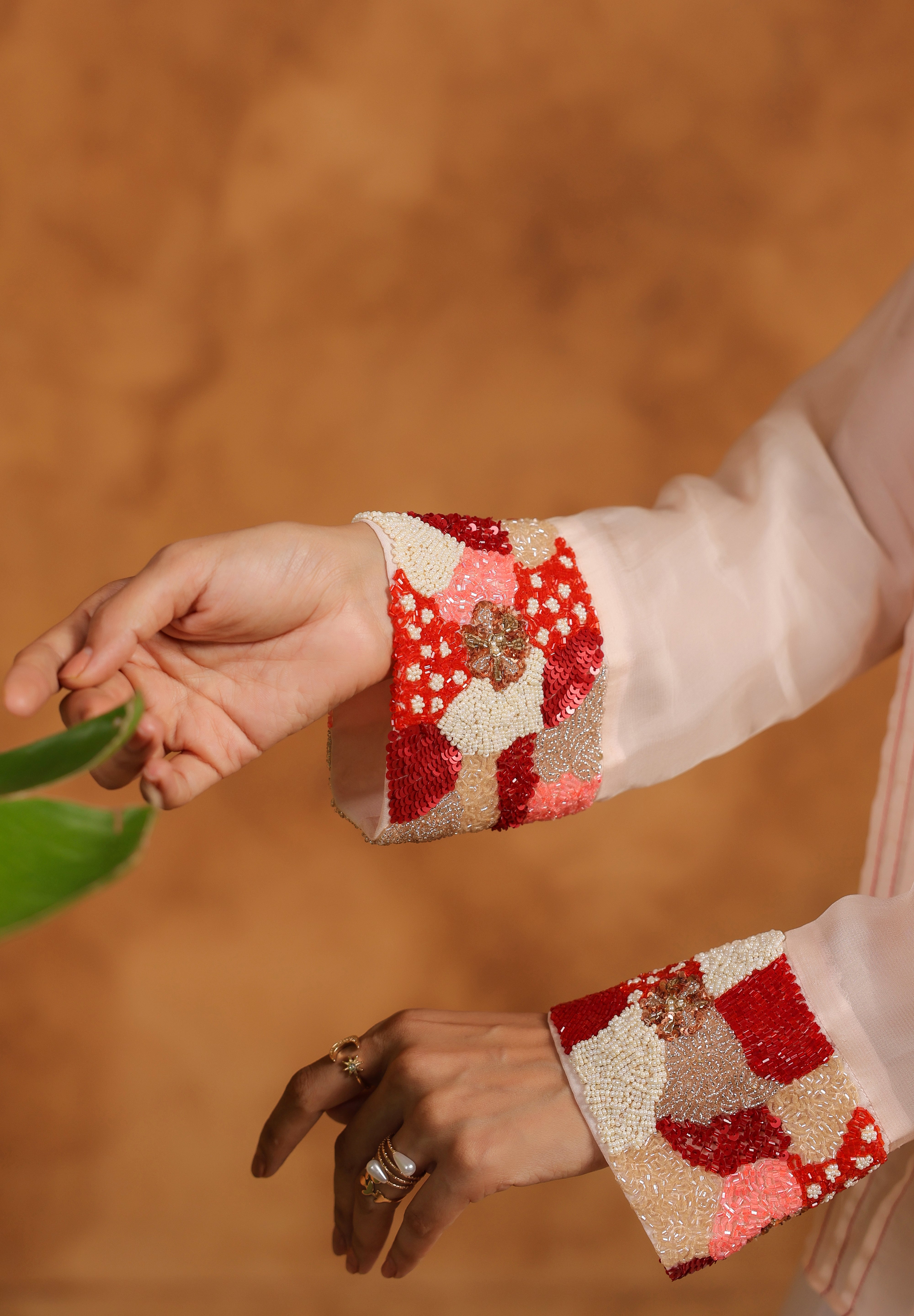 Close-up of hands wearing colorful embroidered cuffs against a warm-toned background