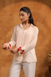 Woman wearing a light pink blouse and white pants against a warm brown background
