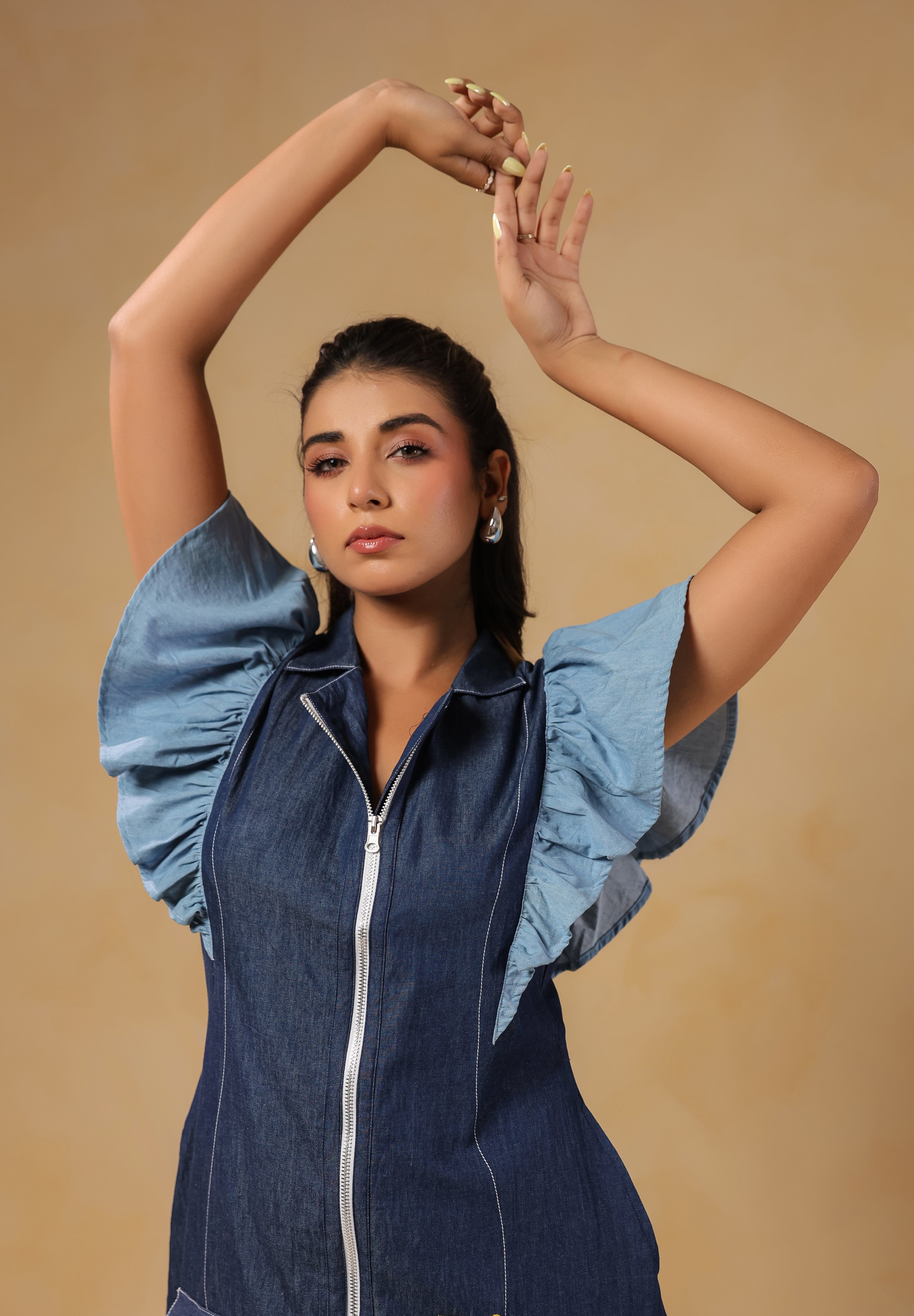 Playful hands-up pose highlighting flutter sleeves and modern denim silhouette