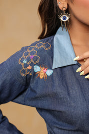 Close-up of shoulder embroidery with honeycomb and honeybee detailing on Hexabee Wrap Top