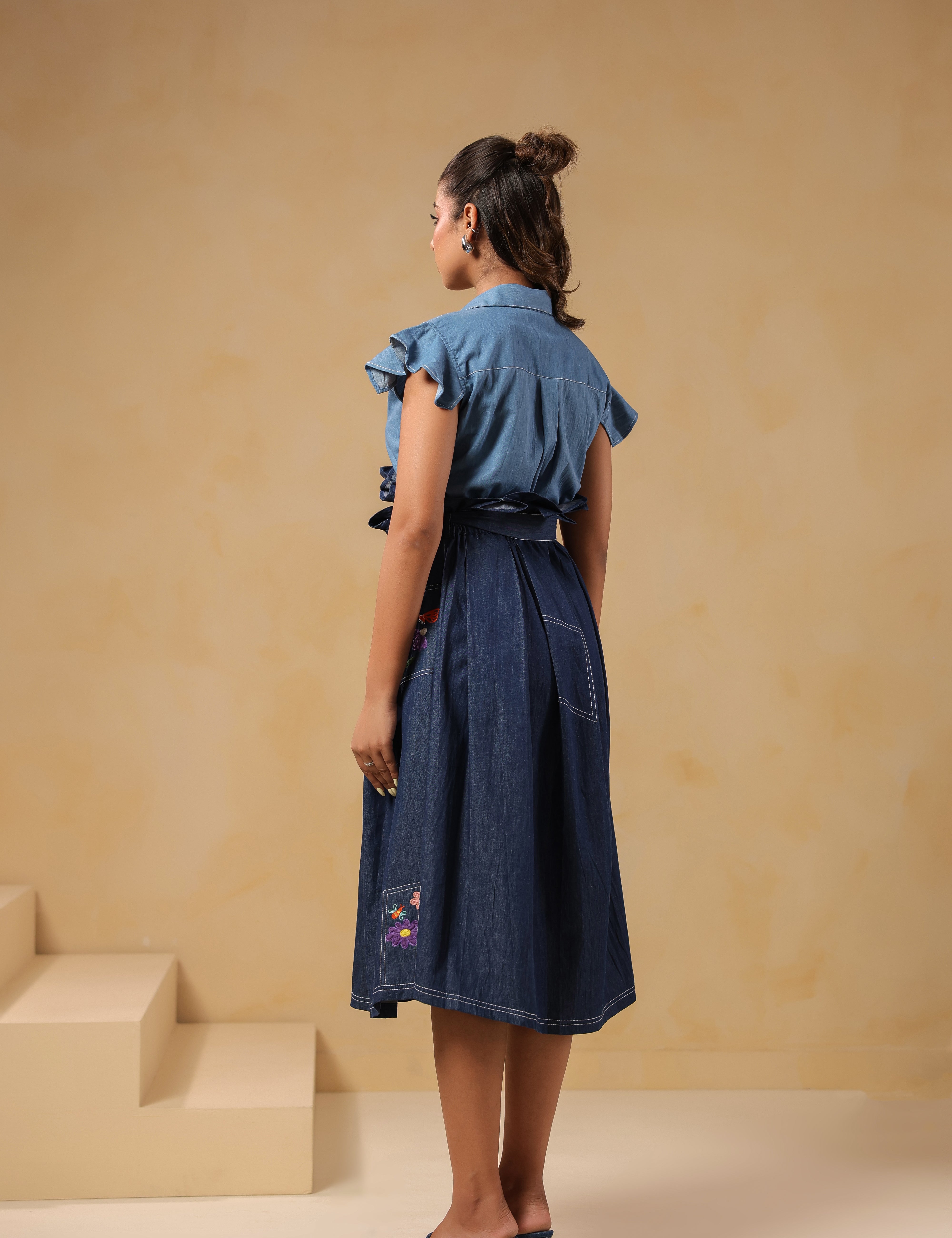 Back view of Ridah’s Meadowflair Coord Set featuring flutter sleeves and pleated A-line skirt with embroidered patchwork pockets — playful yet poised.