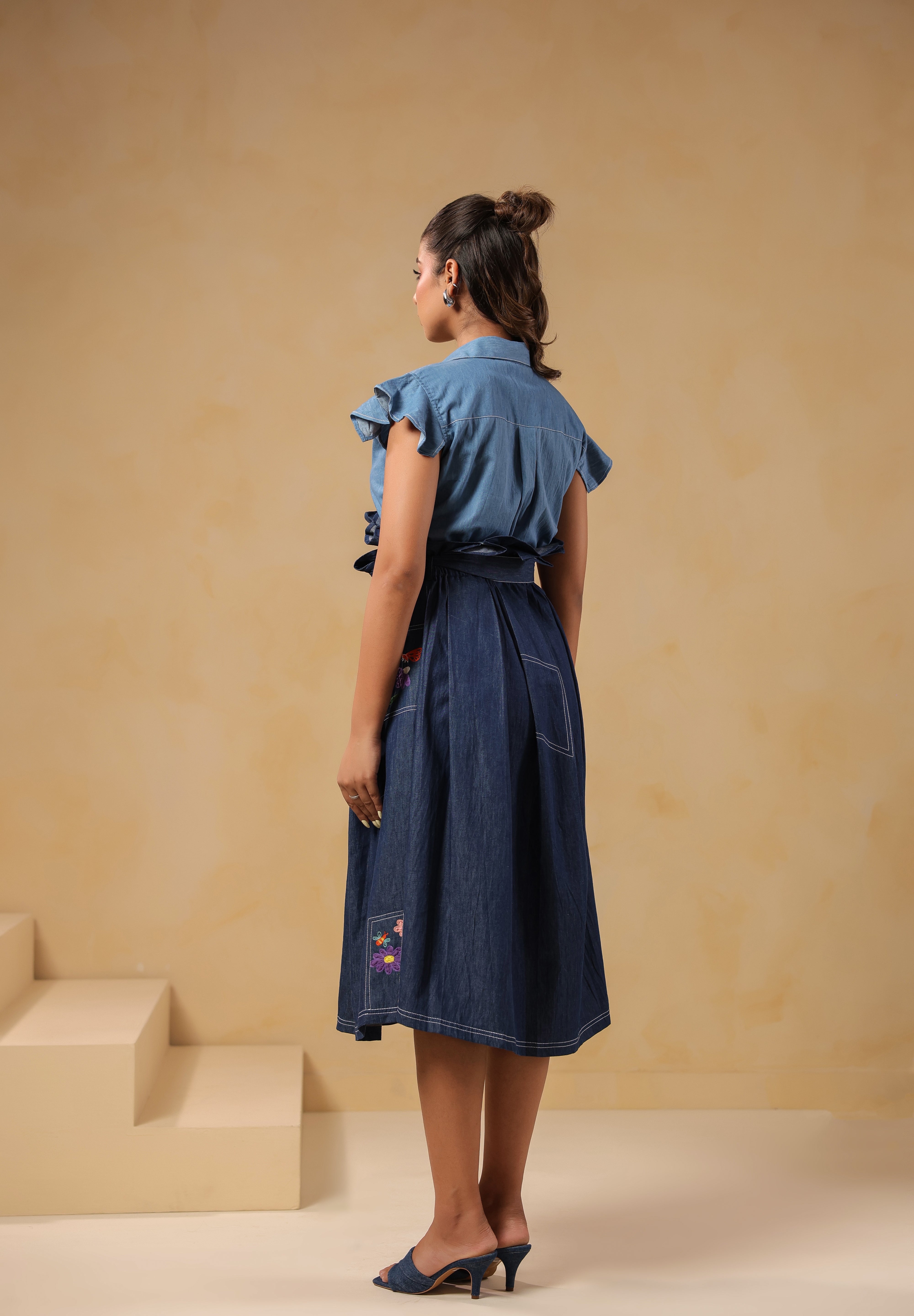 Back view of Ridah’s Meadowflair Coord Set featuring flutter sleeves and pleated A-line skirt with embroidered patchwork pockets — playful yet poised.