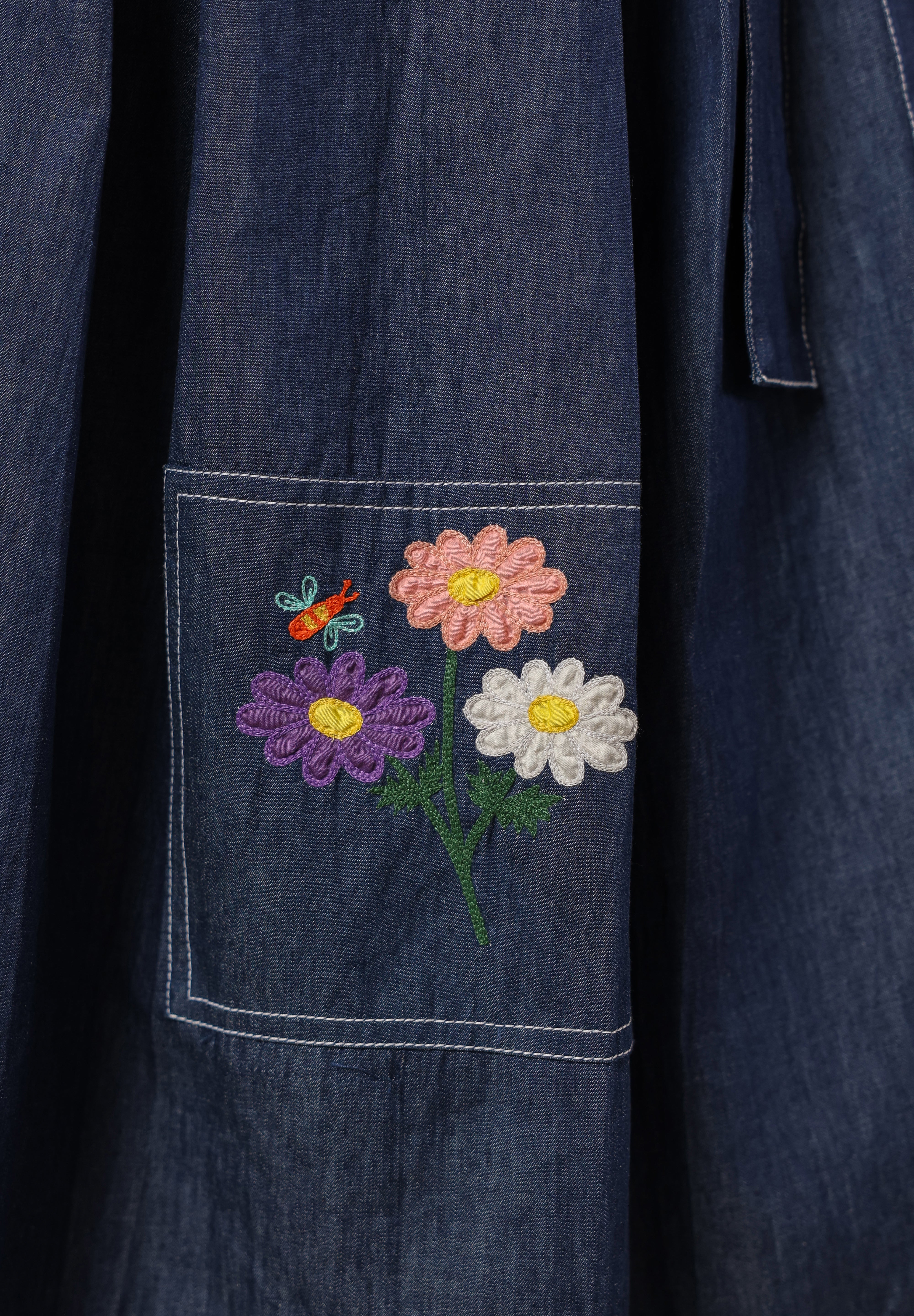 Embroidered daisy trio with pastel butterfly on dark denim pocket — a detail from Ridah’s Meadowflair Coord Set celebrating everyday whimsy.