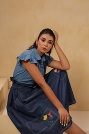 Relaxed sitting pose in Meadowflair Coord Set showing movement, hand-done embroidery and light structure — timeless denim for everyday storytelling.