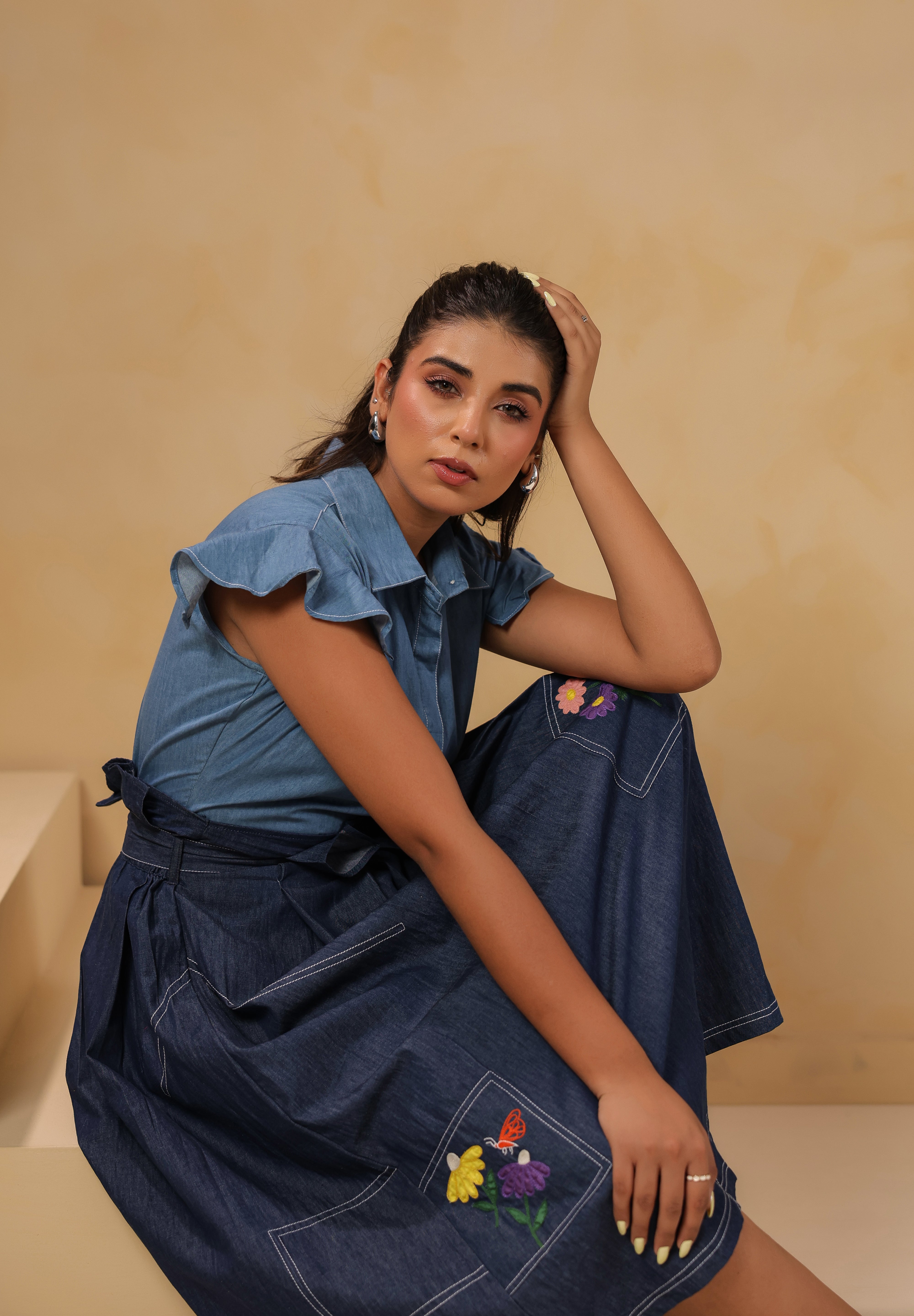 Relaxed sitting pose in Meadowflair Coord Set showing movement, hand-done embroidery and light structure — timeless denim for everyday storytelling.