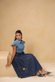 Side-seated pose of model in Ridah’s Meadowflair Coord Set highlighting embroidered motifs, pleats, and ruffle sleeve fall.