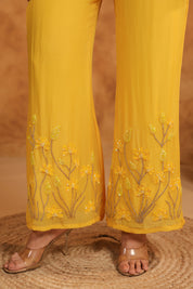 Yellow pants with floral embroidery on a textured surface