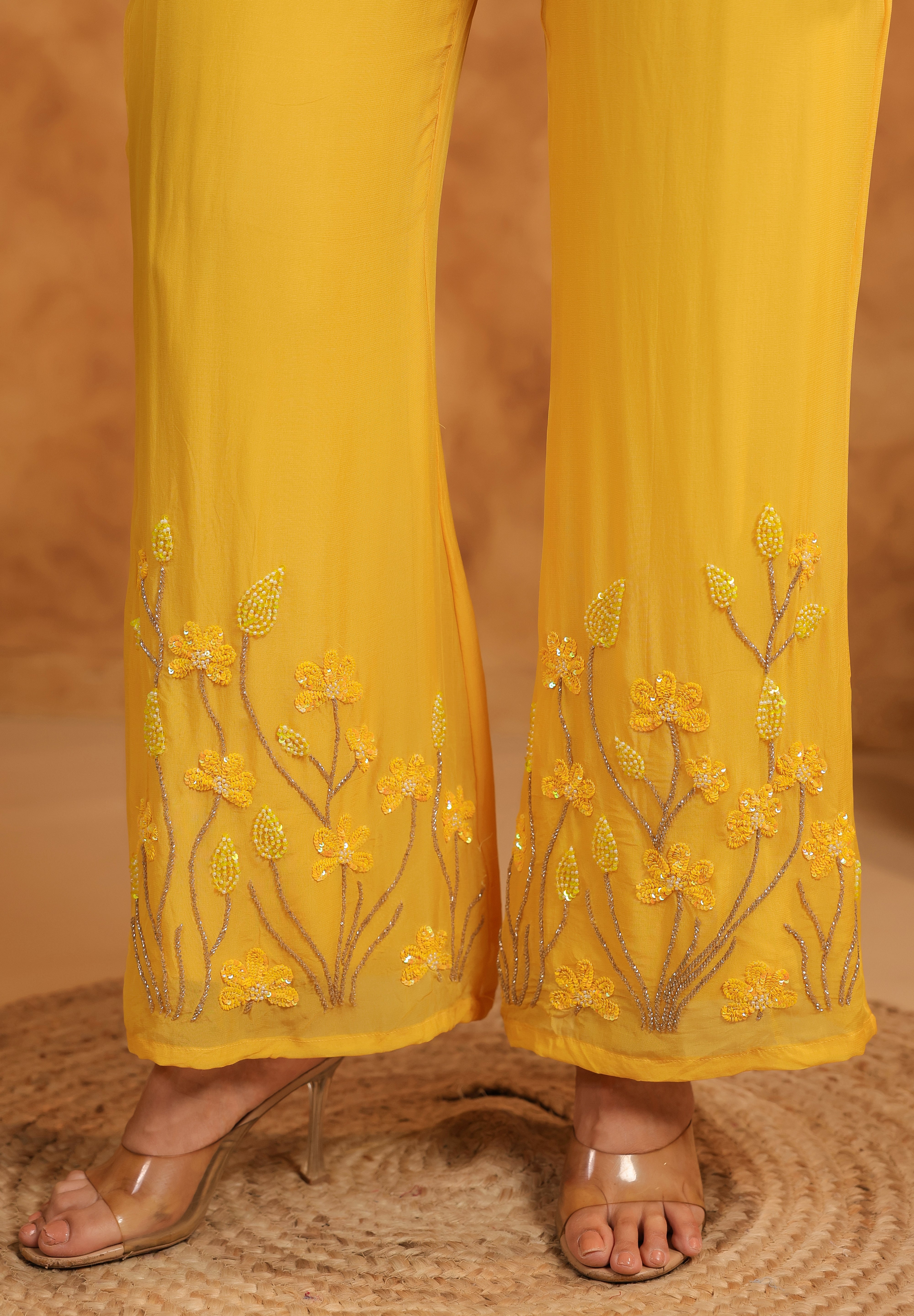 Yellow pants with floral embroidery on a textured surface