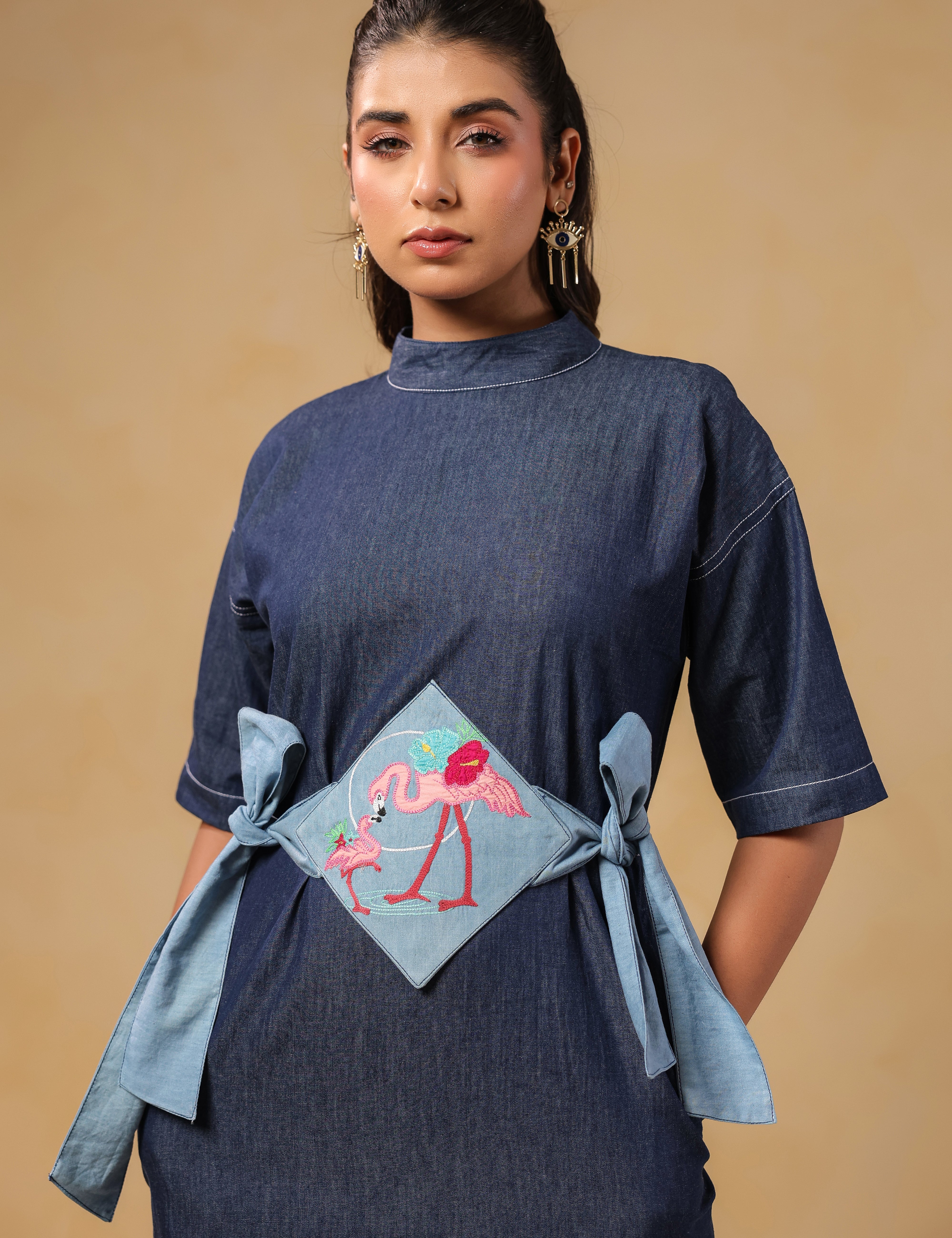 Close-up of embroidered flamingo panel on Tide & Ties Denim Dress waist