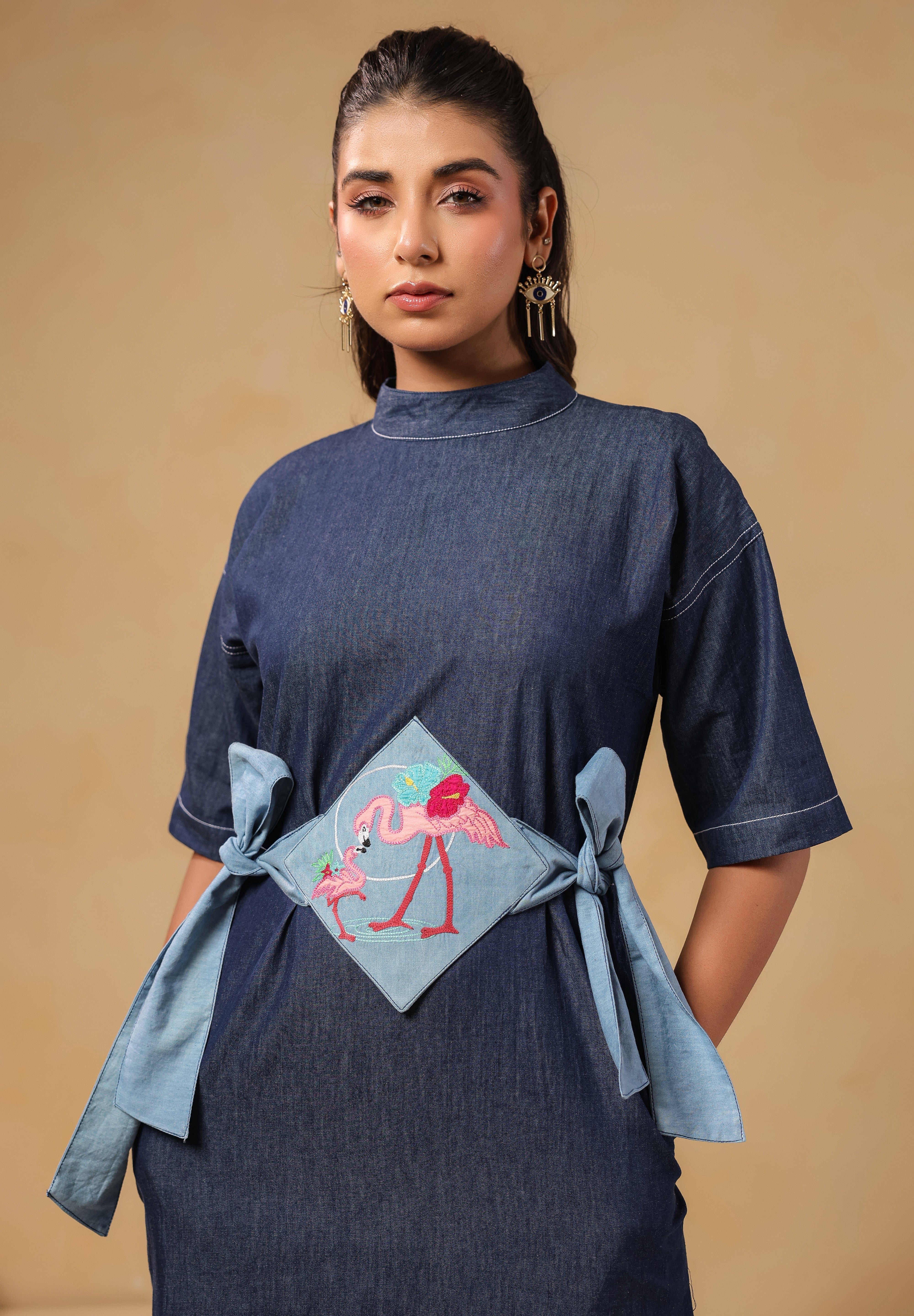 Close-up of embroidered flamingo panel on Tide & Ties Denim Dress waist