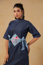 Model in playful pose wearing Tide & Ties Flamingo Dress with dual-tone denim belt