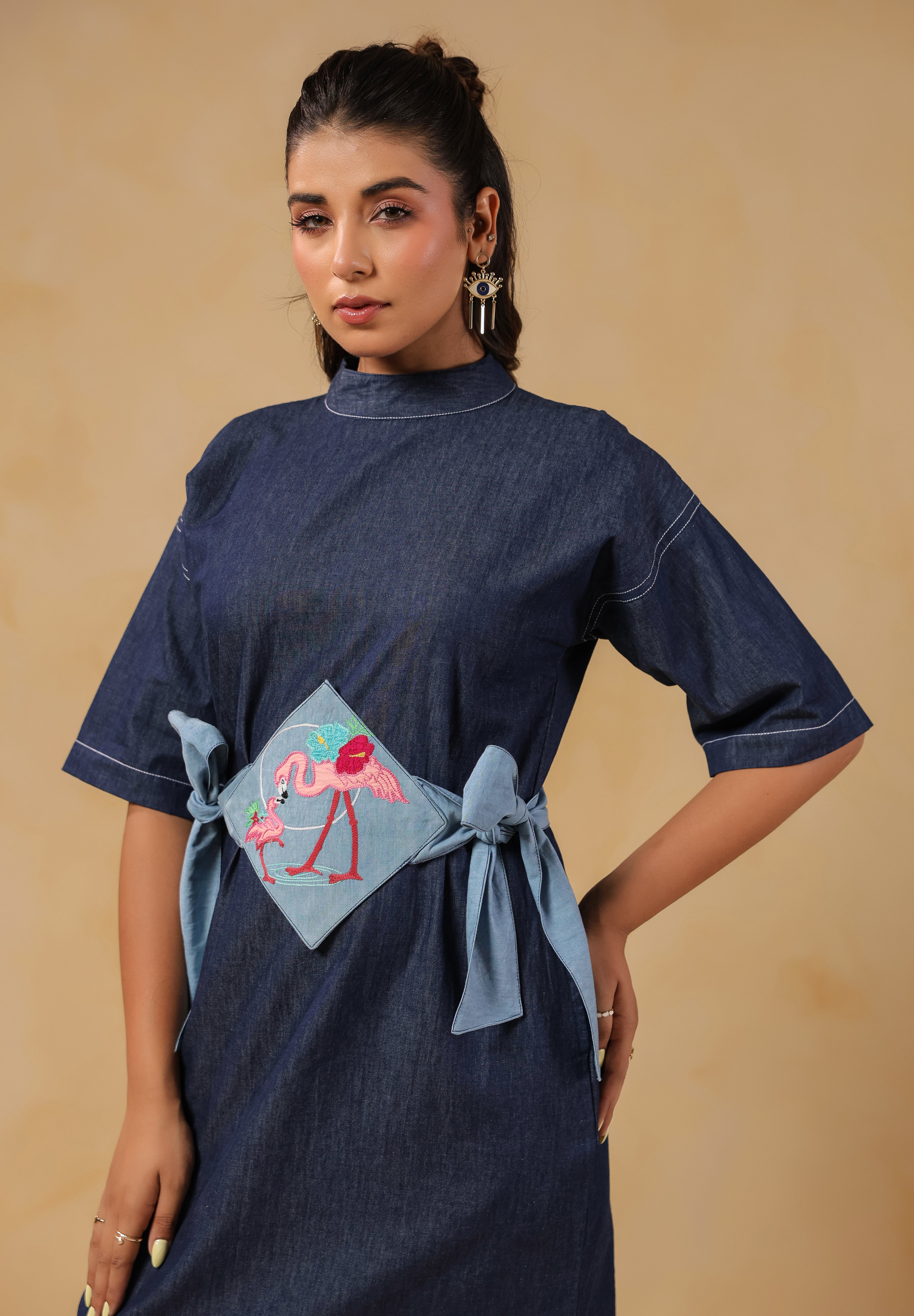 Model in playful pose wearing Tide & Ties Flamingo Dress with dual-tone denim belt