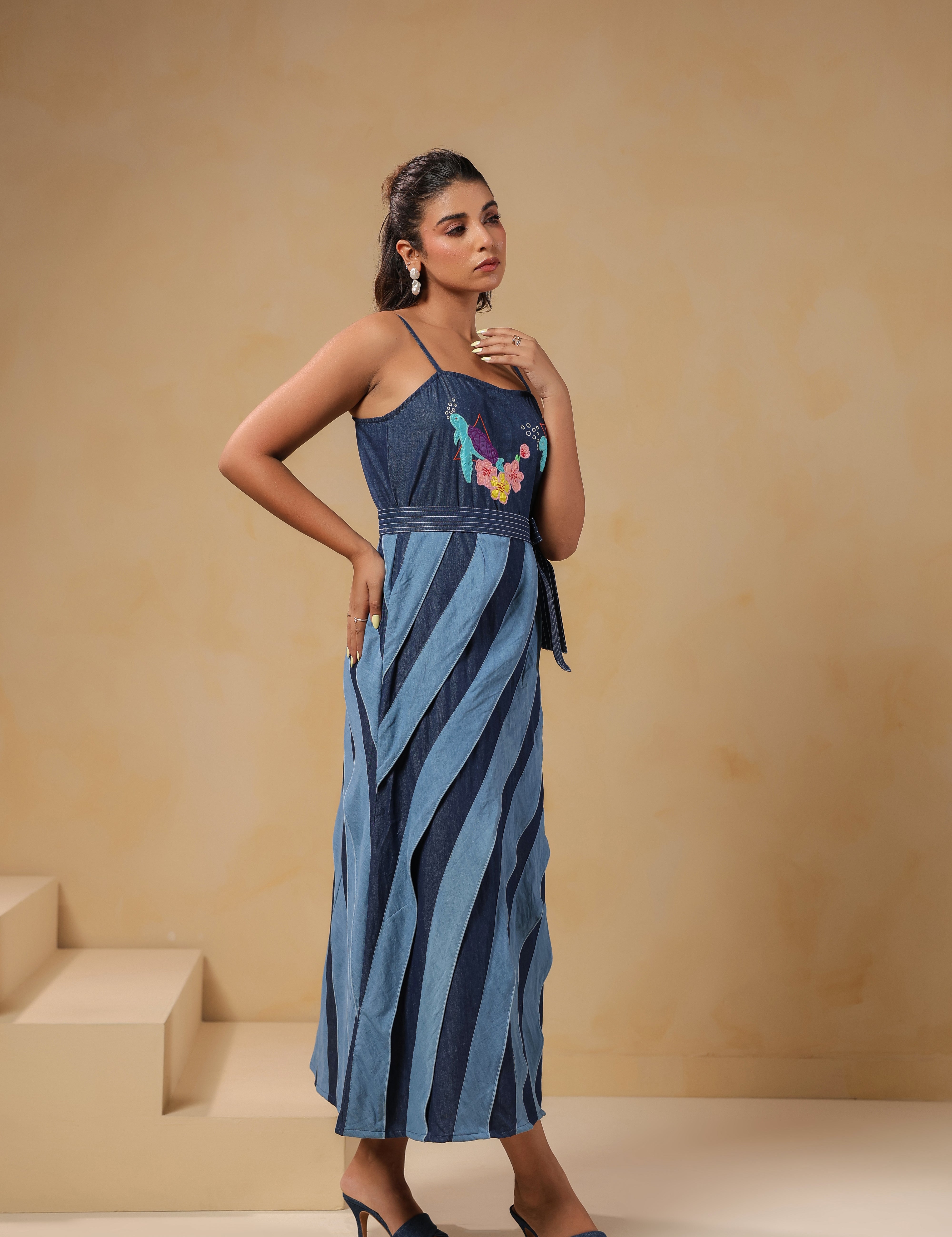 Side profile of Turtletide Flare Dress featuring fitted bodice, waist tie-up belt, and flowing layered denim panels