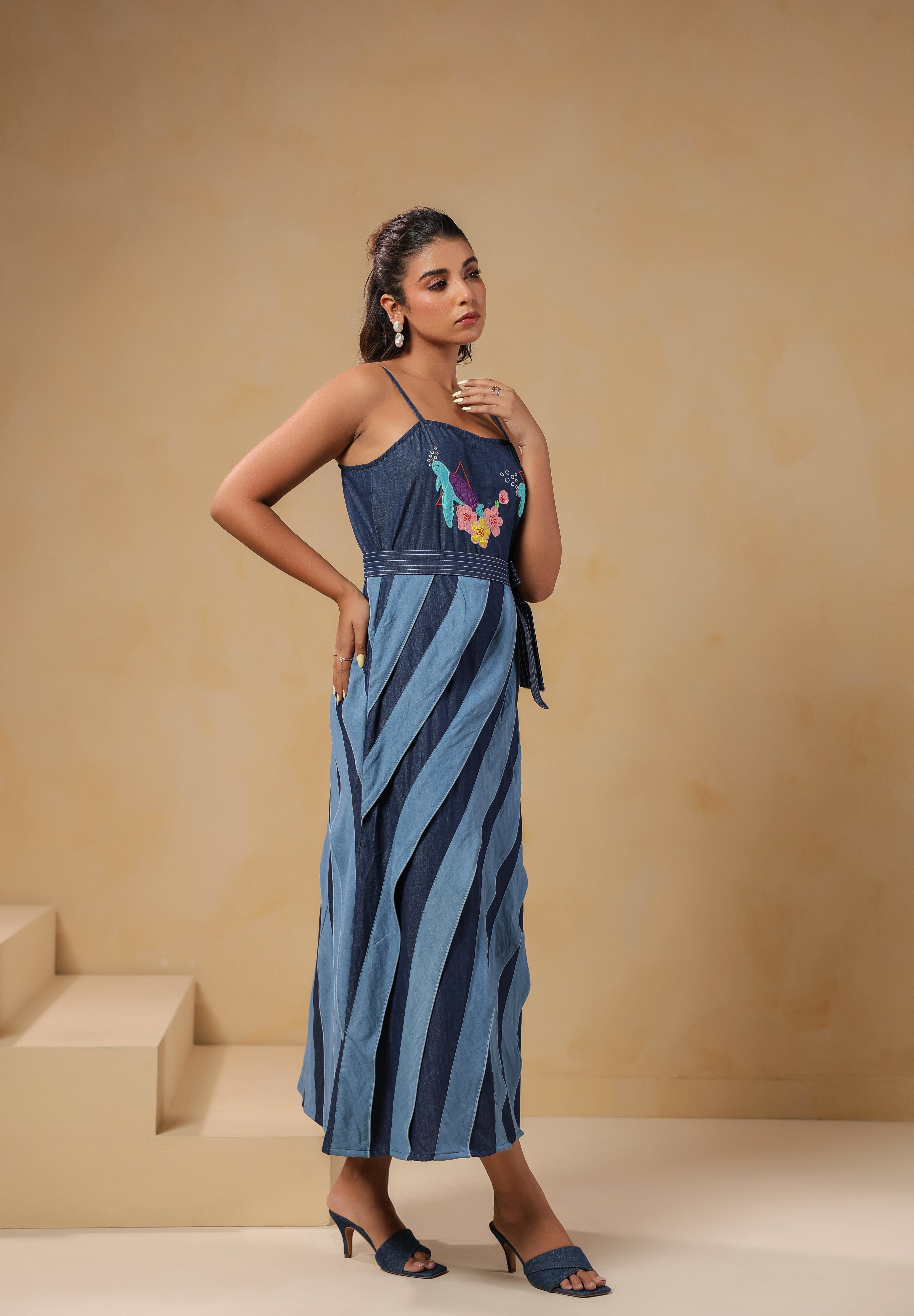 Side profile of Turtletide Flare Dress featuring fitted bodice, waist tie-up belt, and flowing layered denim panels